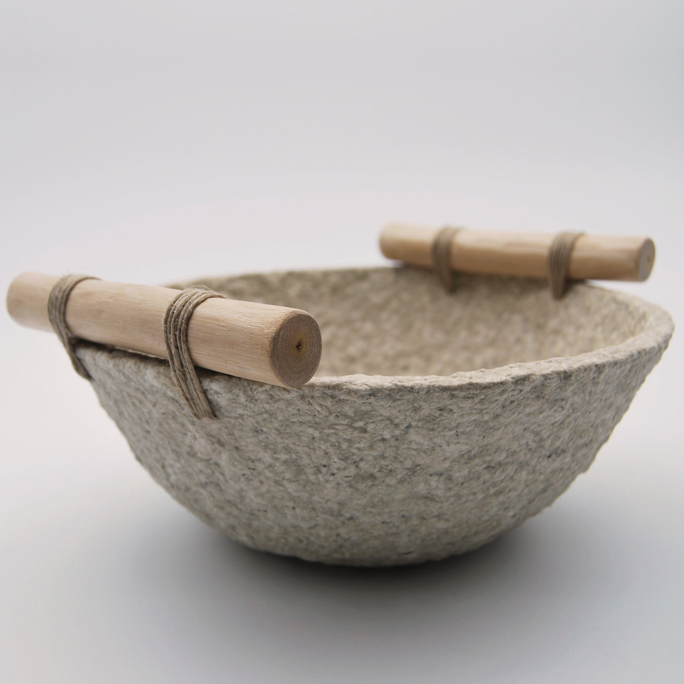 vista lateral cuenco mediano de papel maché color beige natural material reciclado con asas de madera y fío de cáñamo hecho a mano en Galicia artesanía sostenible